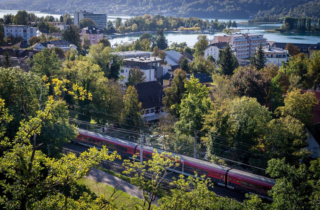 Roter Railjet durch Pörtschach mit See im Hintergrund