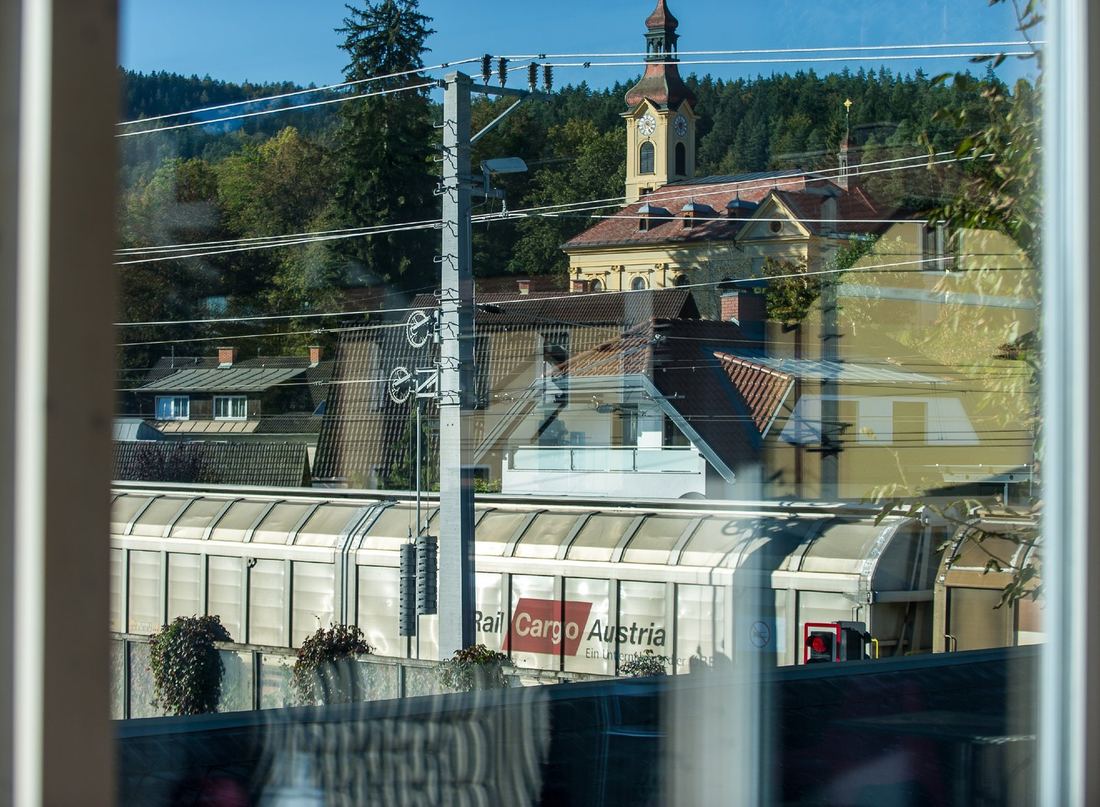 Güterzug verstellt aus dem Fenster die Sicht auf die Pörtschacher Kirche